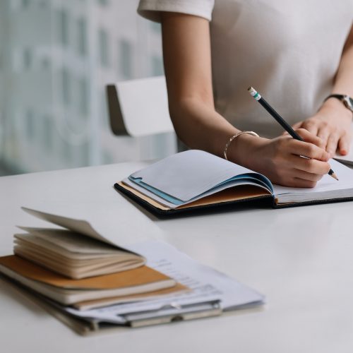 Close up of a woman writer hand writing in a notebook at home